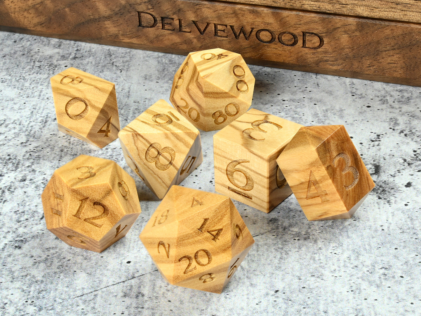 Olivewood dice set for dnd rpg tabletop gaming in front of Delvewood delver's kit dice box.