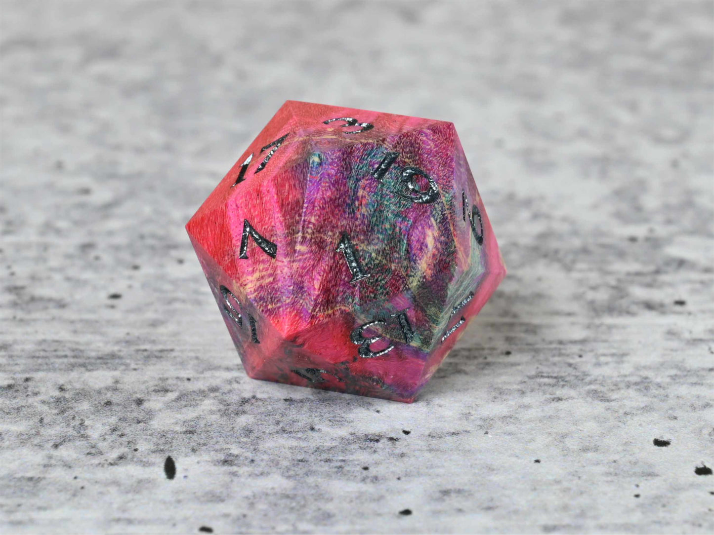 Pink, purple, and blue dye stabilized box elder burl wood d20 with black painted numbers for dnd ttrpg