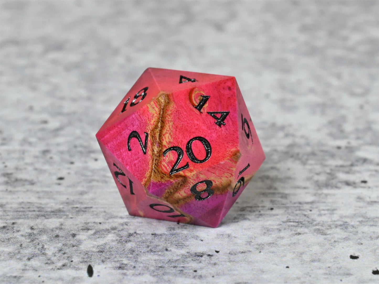 Pink and teal dye stabilized buckeye burl wood d20 with black painted numbers for dnd ttrpg
