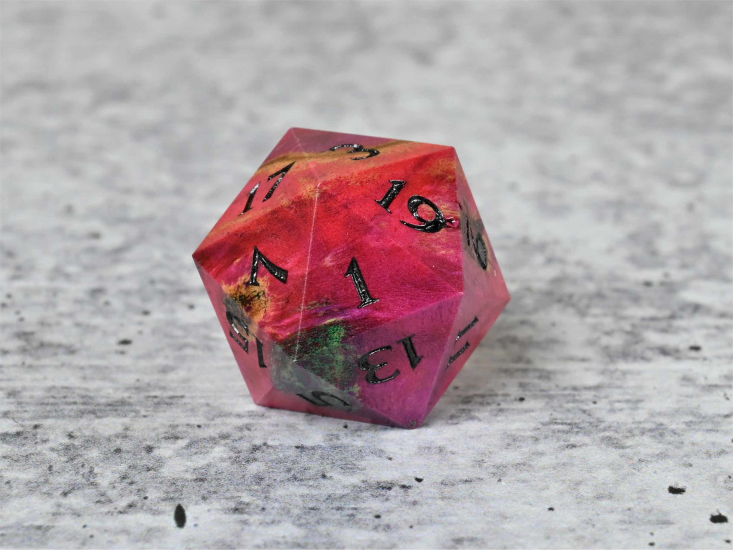 Pink and teal dye stabilized buckeye burl wood d20 with black painted numbers for dnd ttrpg