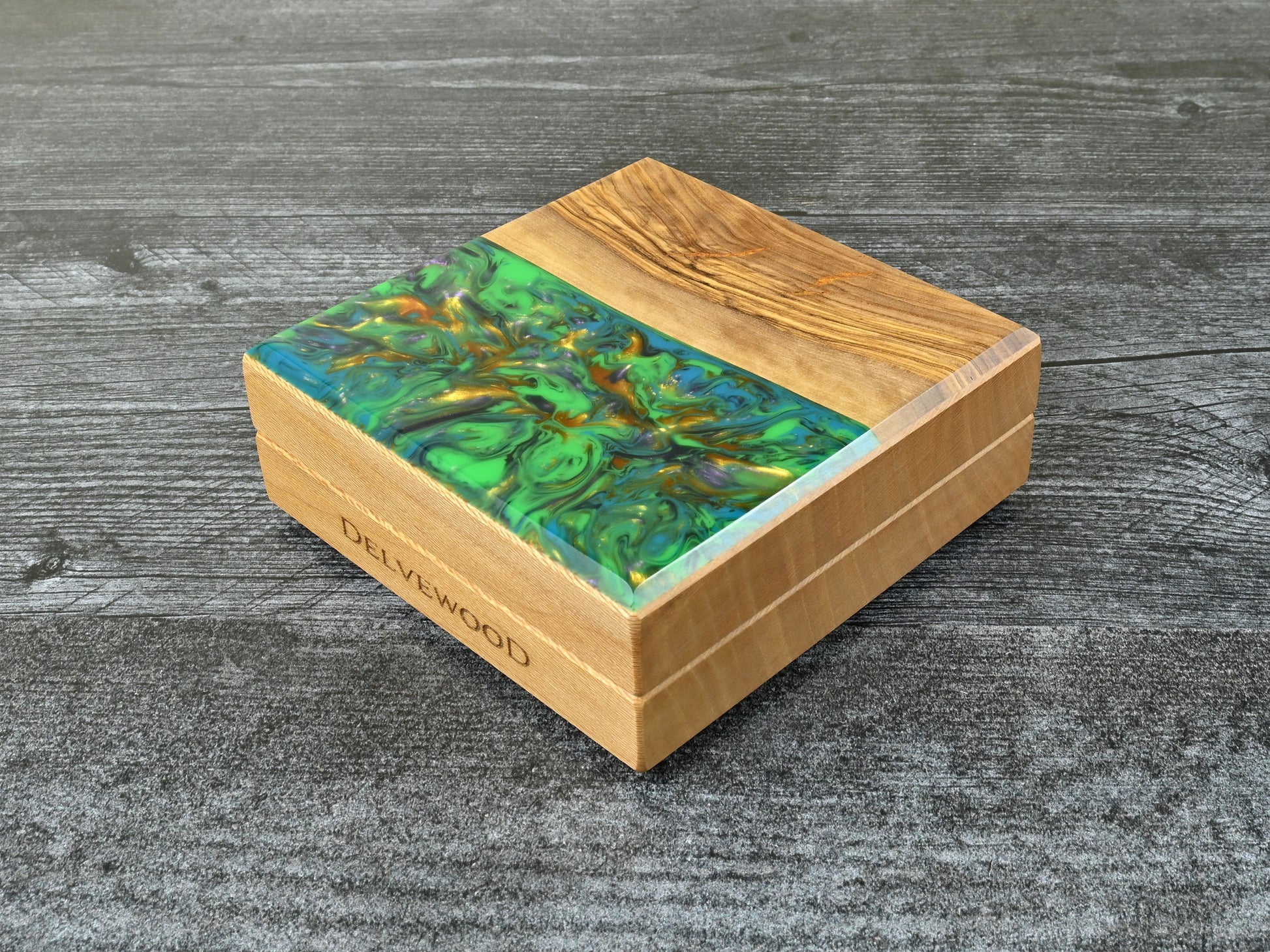 This Little Delver Dice Box features a sycamore wood core and an olivewood top veneer with green, turquoise, purple, and gold resin.  D&D ttrpg.