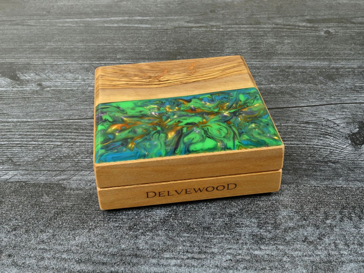 This Little Delver Dice Box features a sycamore wood core and an olivewood top veneer with green, turquoise, purple, and gold resin. D&D ttrpg.