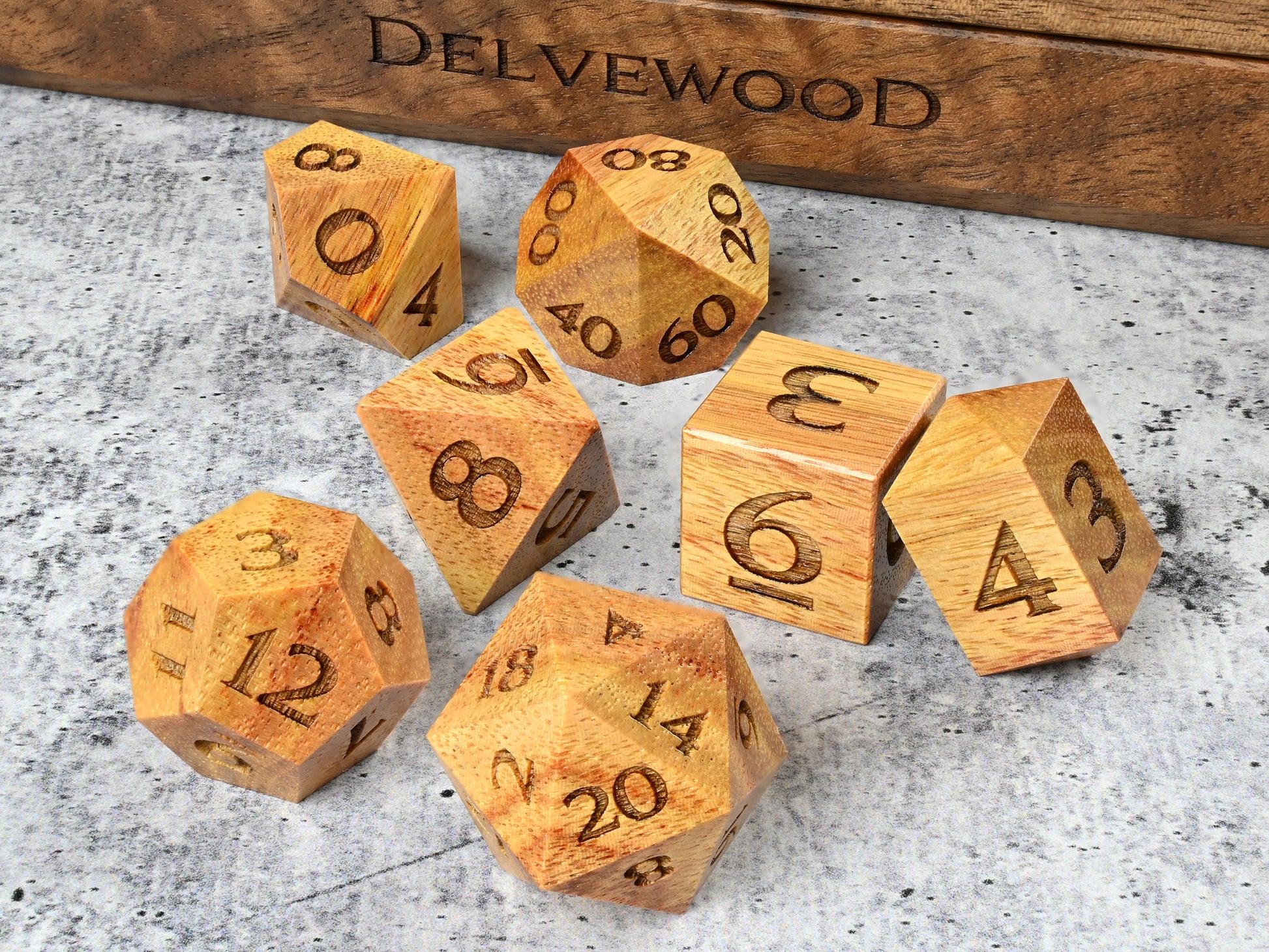 Canarywood dice set for dnd rpg tabletop gaming in front of Delvewood delver's kit dice box.