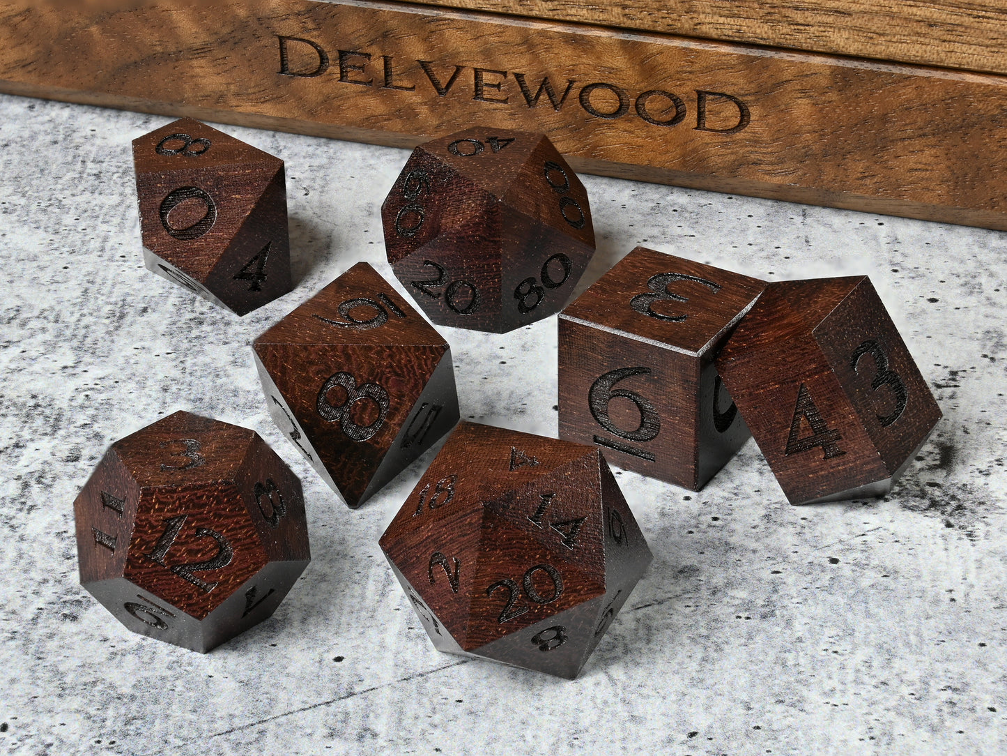 Katalox wood dice set for dnd rpg tabletop gaming in front of Delvewood delver's kit dice box.
