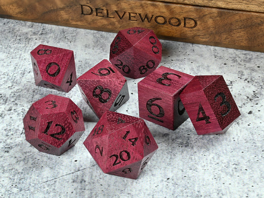 Purpleheart wood dice set for dnd rpg tabletop gaming in front of Delvewood delver's kit dice box.