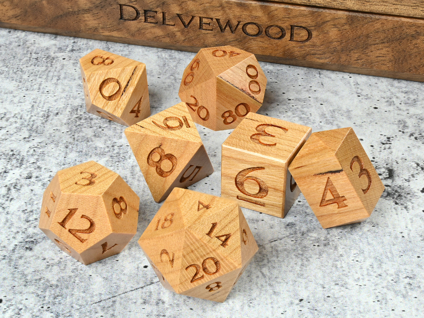 Cherry wood dice set for dnd rpg tabletop gaming in front of Delvewood delver's kit dice box.